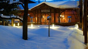 Un edificio de madera con un letrero en la fachada, rodeado de nieve.