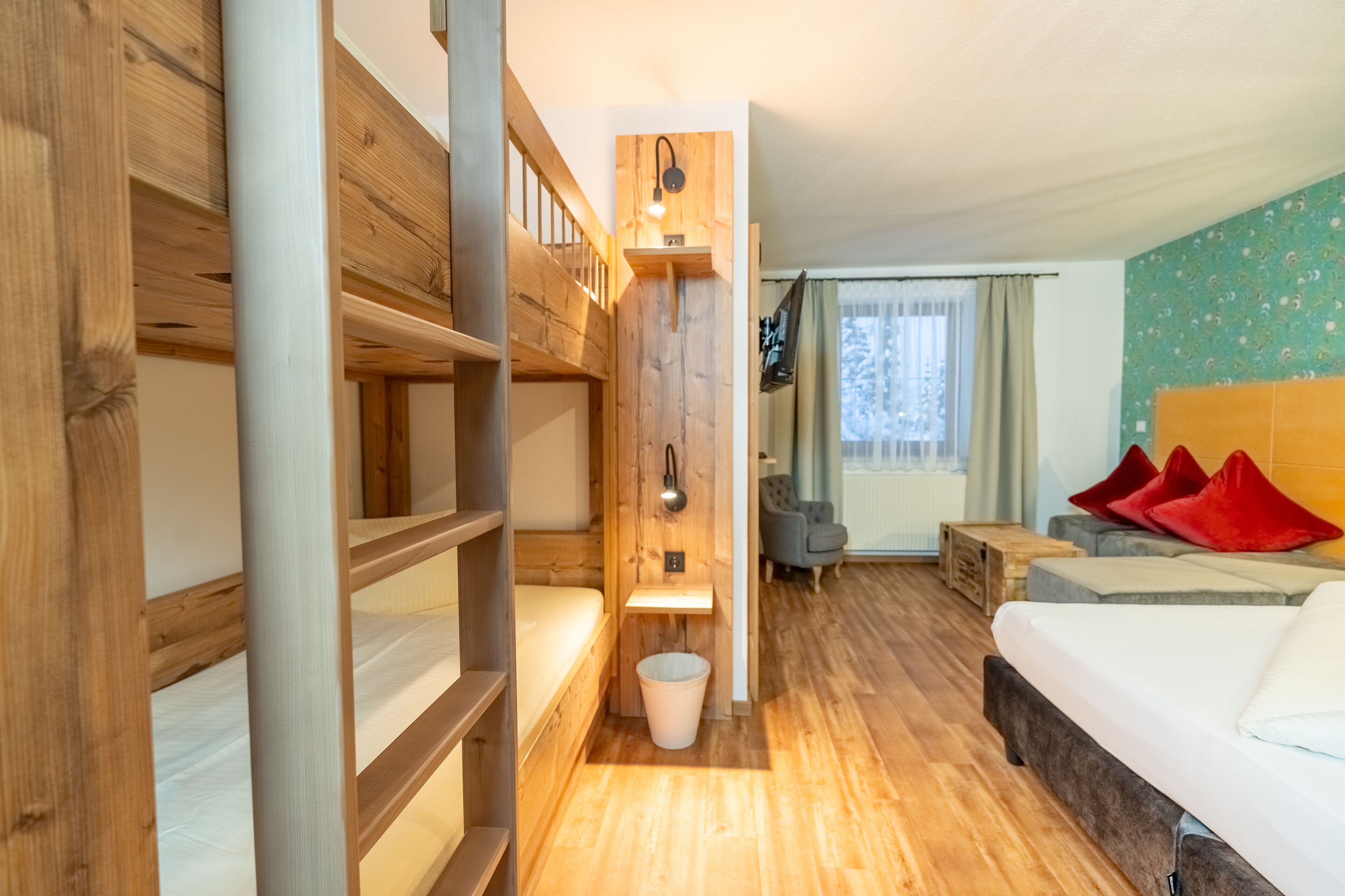 Ein Zimmer mit einem Etagenbett, einem Einzelbett, einem kleinen Tisch und einem Stuhl.