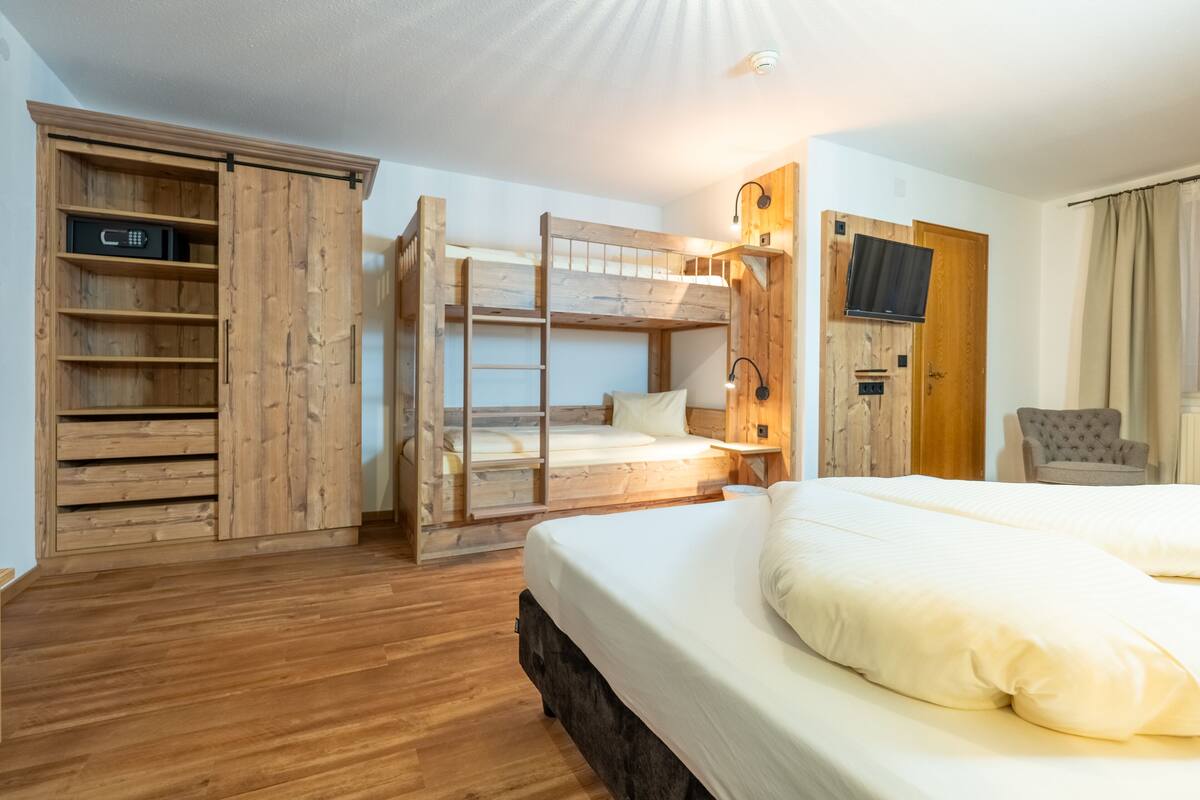 A wooden bunk bed room with a TV and a chair.