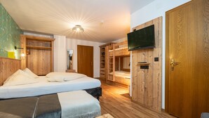 Un dormitorio con literas, paredes de madera, un televisor montado en la pared y una puerta de madera.
