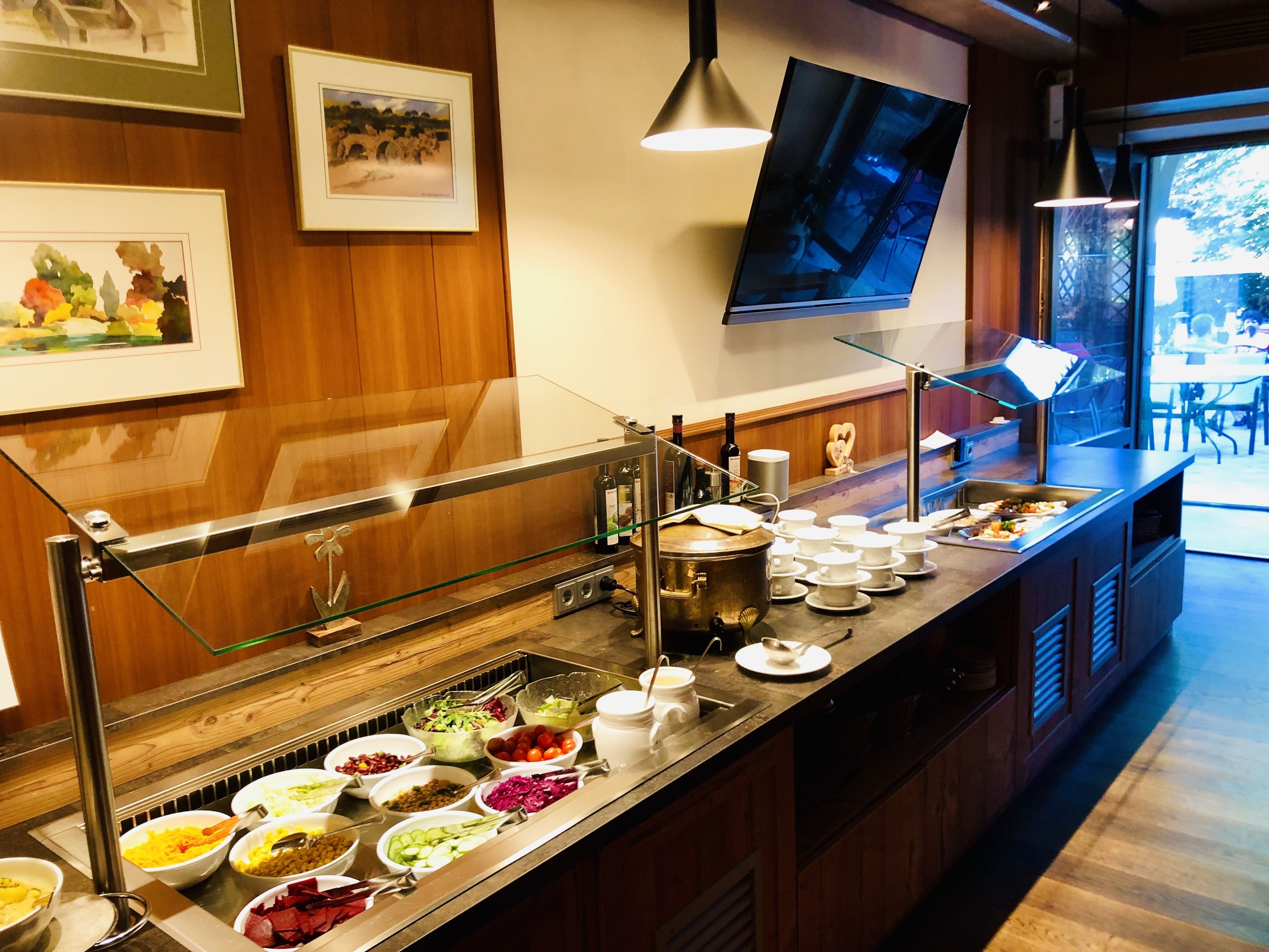 A buffet setup with various food items and a television screen in the background.