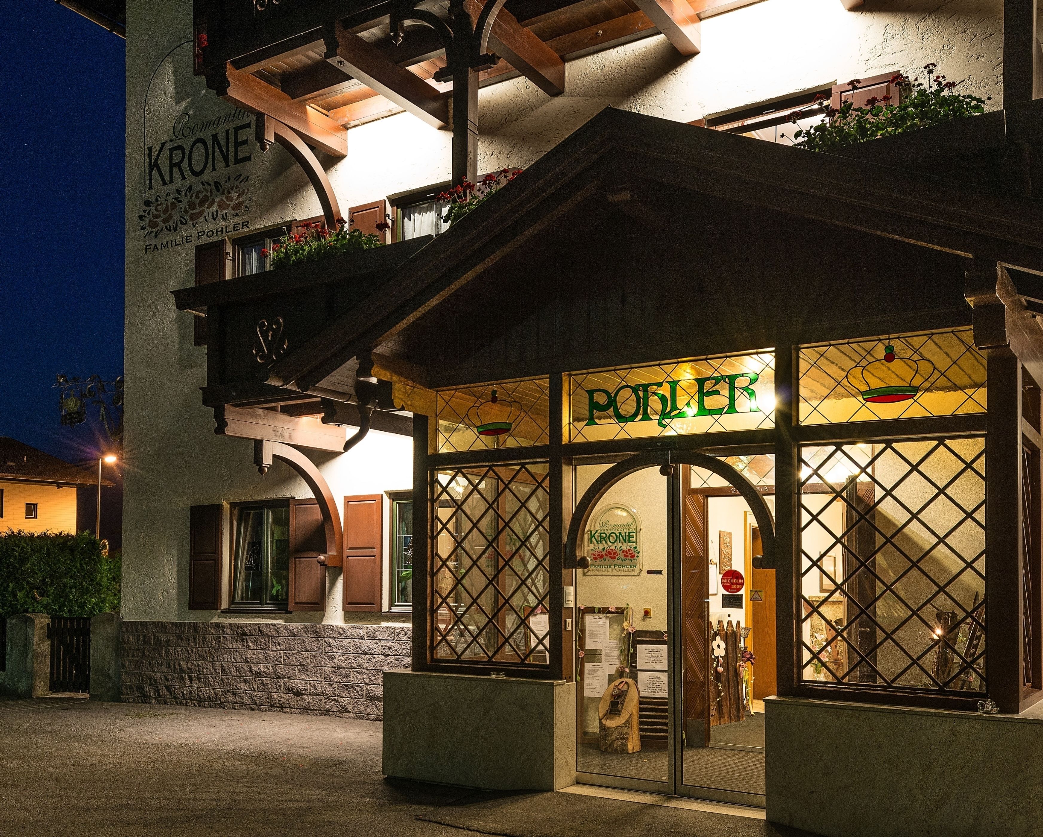 L’entrée d’un hôtel, avec une enseigne indiquant « KRONE » et « FAMILIE POHLER ».