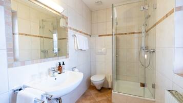 A modern bathroom with a glass-enclosed shower, a white sink, and a toilet.
