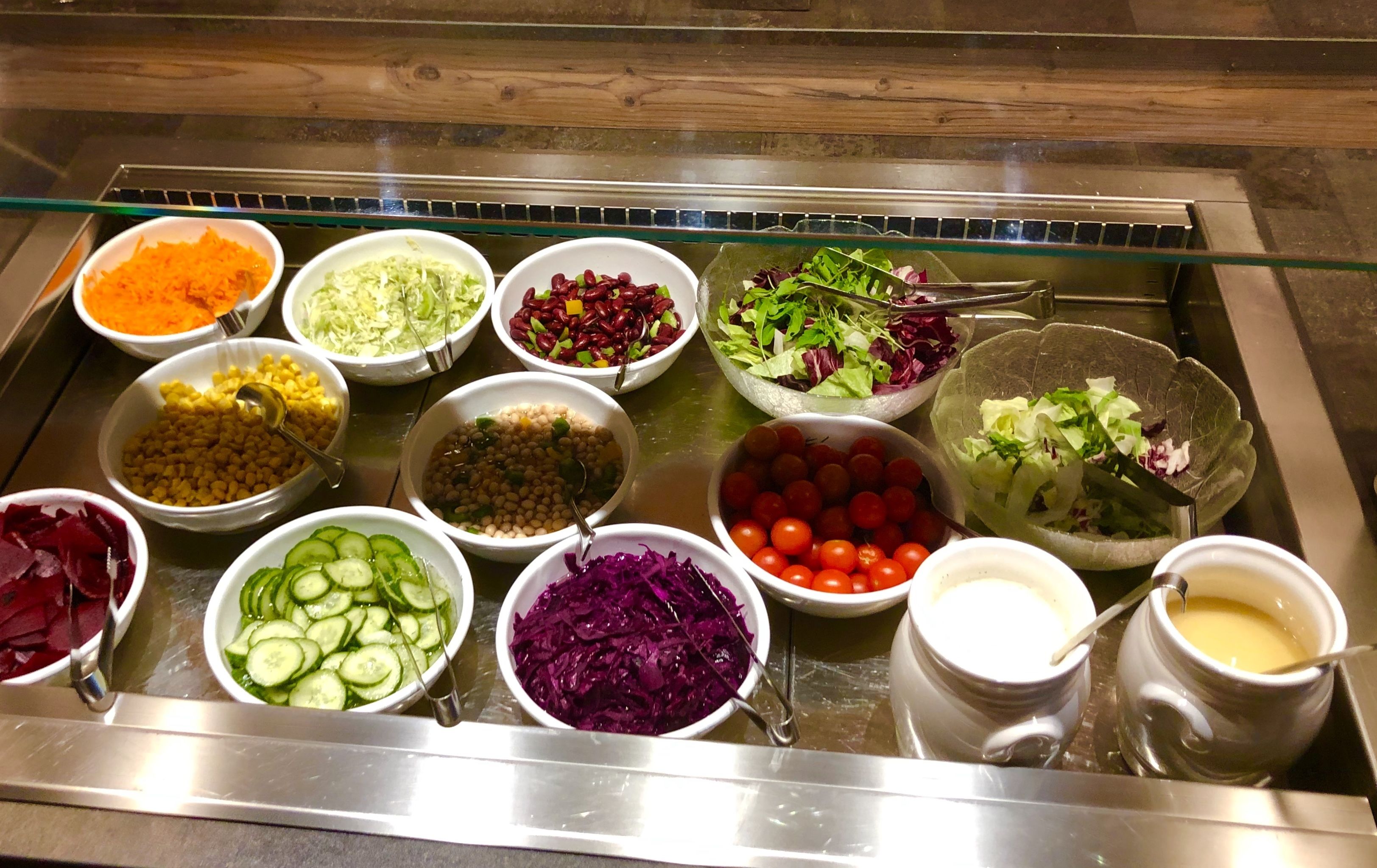 A buffet with various food options including salads, vegetables, and dips.