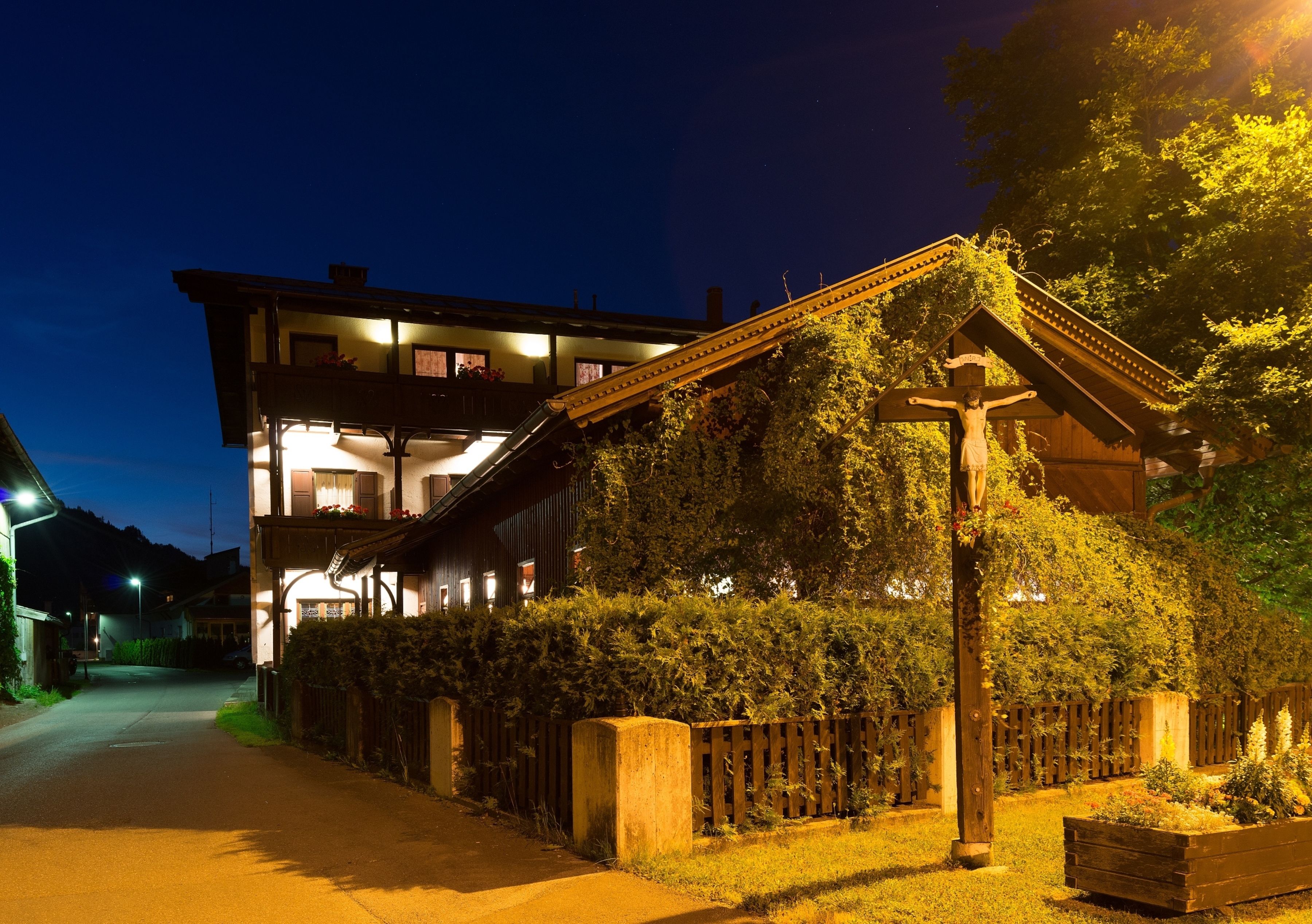 A building with a balcony, a wooden fence, and a well-lit street at night.