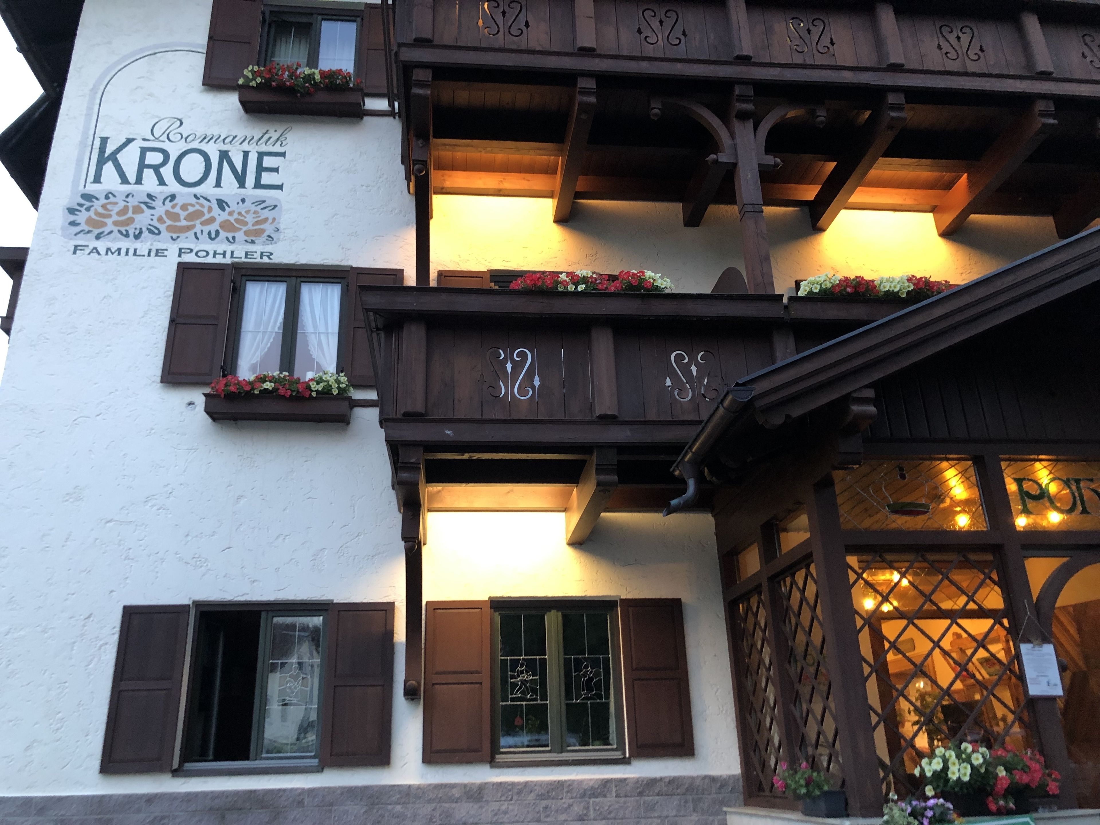 Ein traditionelles Gebäude mit hölzernen Balkonen, Blumenkästen und einem Schild mit der Aufschrift "Familie Pohler".