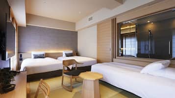 A modern hotel room with two beds, a wooden chair, a small table, and a large window with a view of the city.