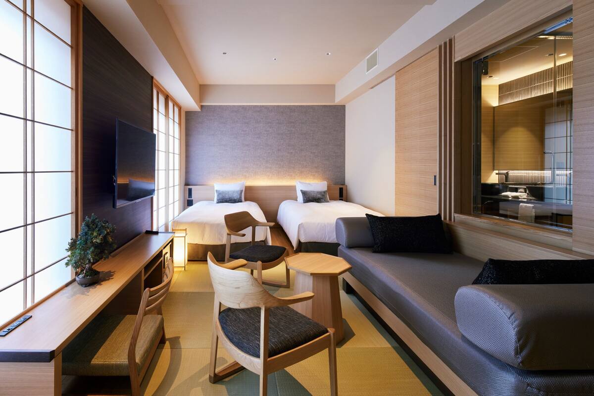 A modern hotel room with a large bed, a sofa, a desk, and a TV.