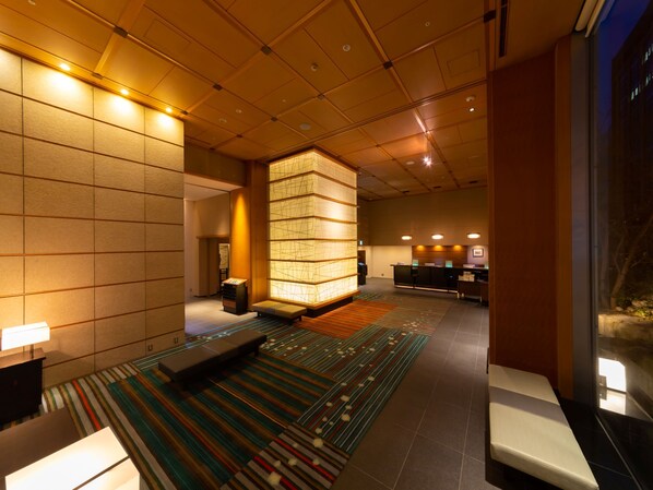 A hotel lobby with a reception desk, seating area, and a large illuminated wall. - Hotel Niwa Tokyo (Tokyo)