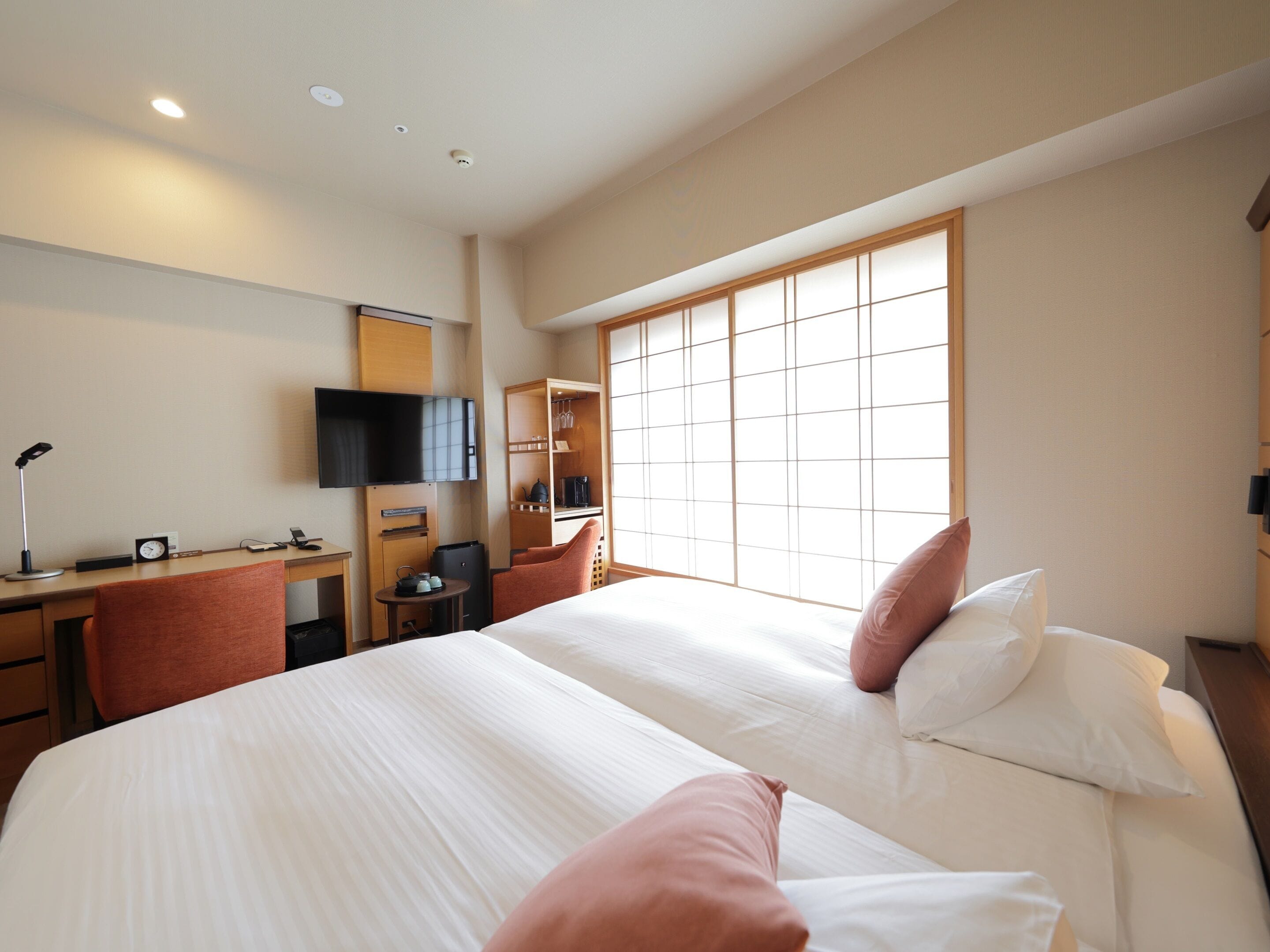 Habitación de hotel con una cama grande, un escritorio con computadora, una silla, un televisor y un armario.