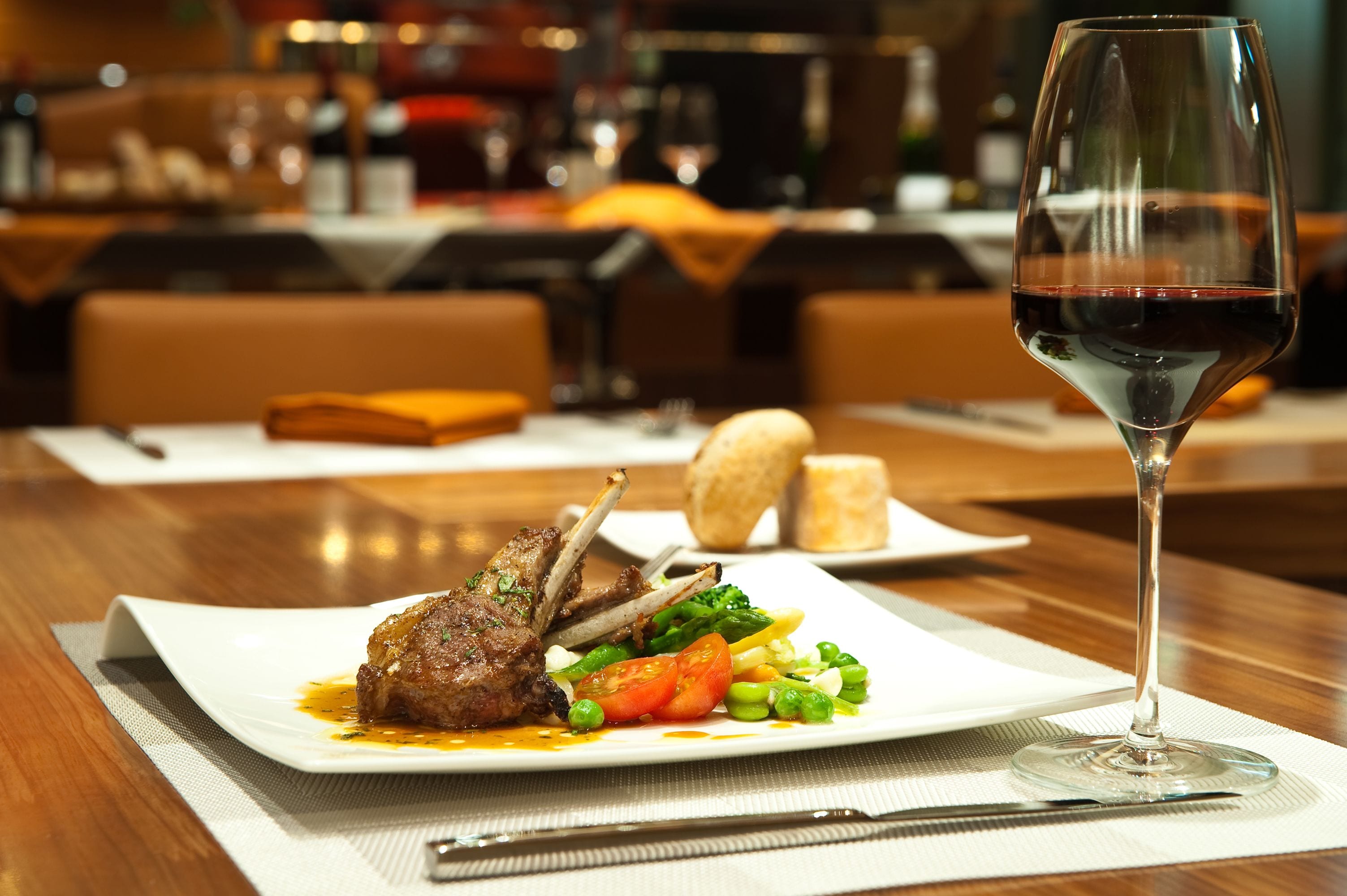A dining table with a plate of food, a glass of red wine, and a knife.