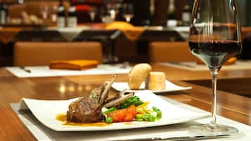 Una mesa con un plato de comida, una copa de vino tinto y un cuchillo.