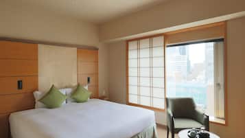 A hotel room with a large bed, a chair, a small table with a tray, and a sliding glass door to the outside.