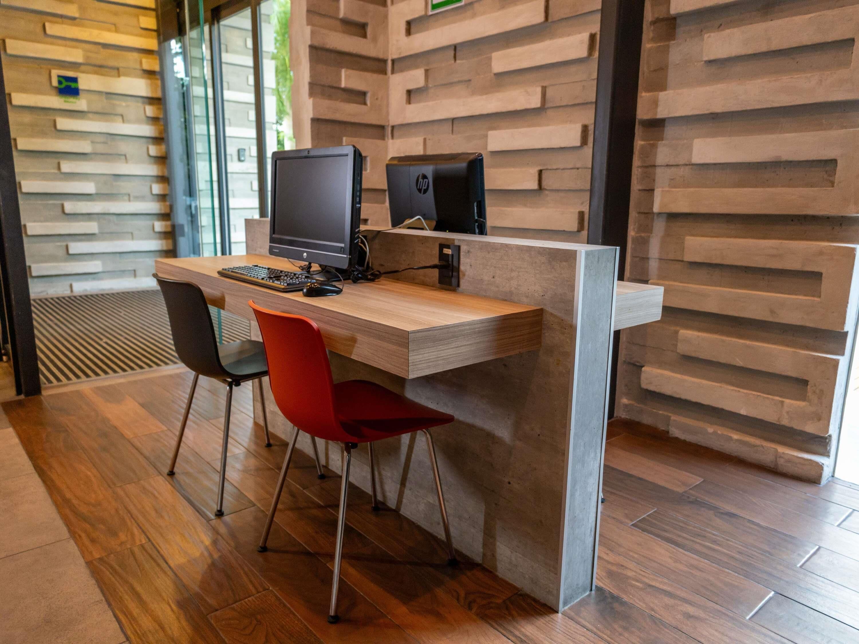 A modern workspace with a wooden desk, two chairs, a computer, and a coffee machine.