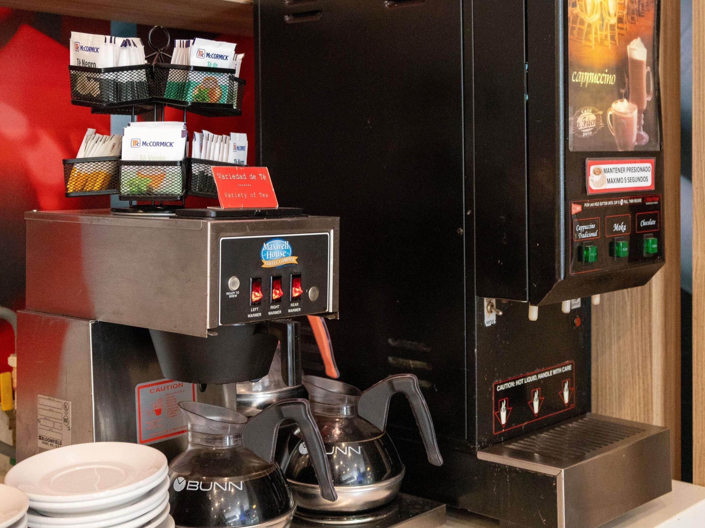 A coffee machine with a variety of coffee options and a sign indicating a variety of tea.