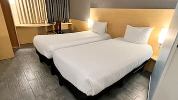 Habitación de hotel con dos camas, un escritorio y una silla.