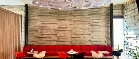 A modern interior with a red sofa, white and black chairs, and a unique ceiling design.