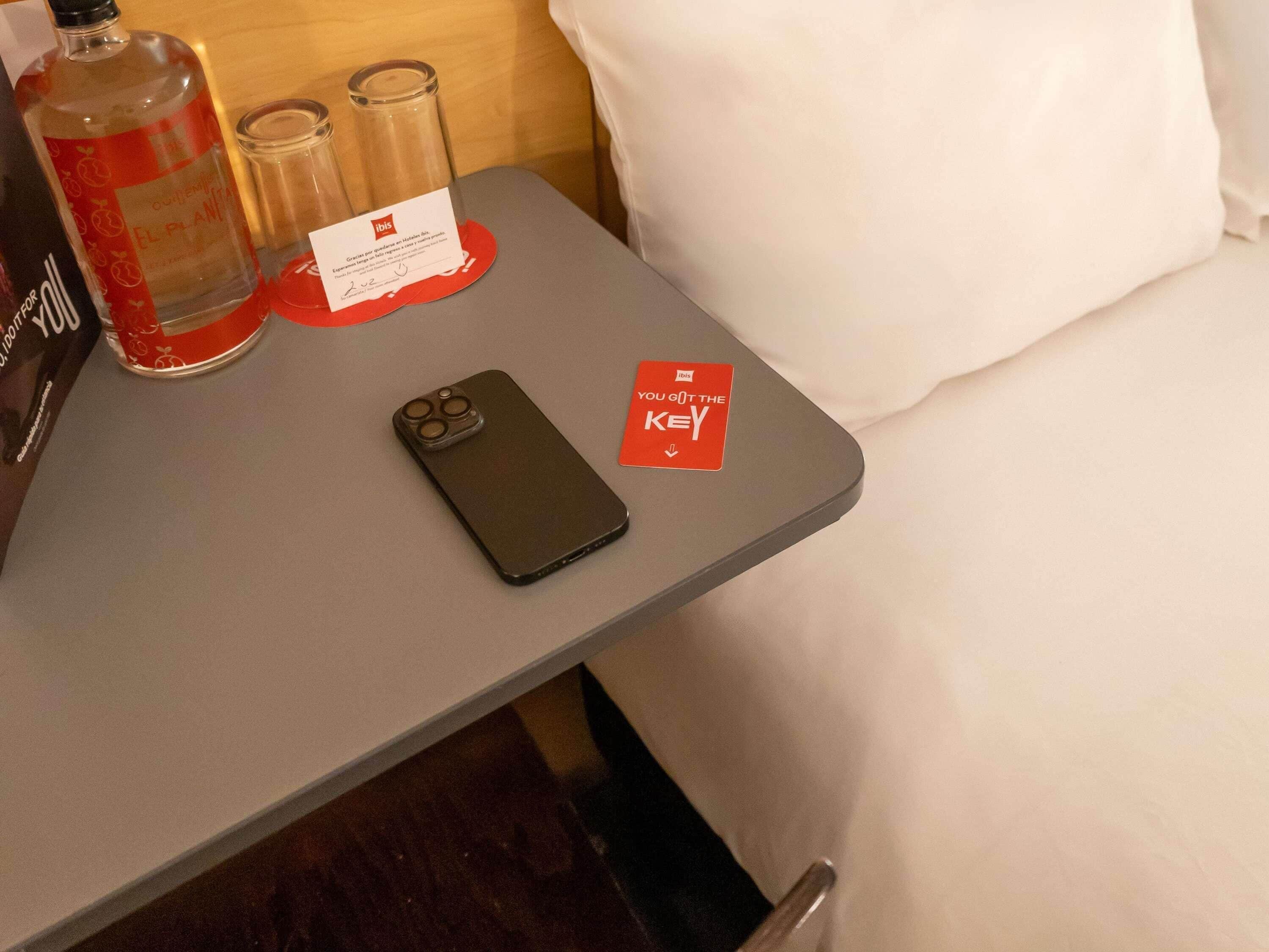 A smartphone on a table with a 'You Got the Key' sign, a bottle, and two glasses.