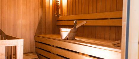 A sauna with wooden benches and a bucket.