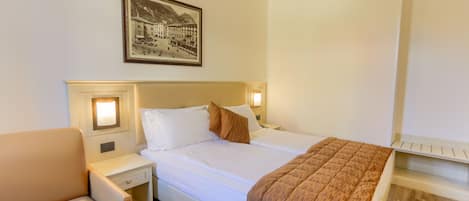 Une chambre d’hôtel avec un lit, une table de chevet, une chaise et un tableau encadré au mur.
