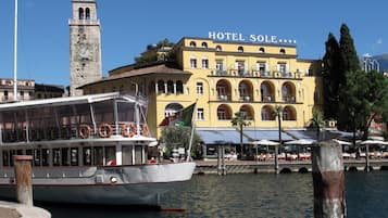 A boat docked at a pier with a yellow building labeled "HOTEL SOLE" in the background.