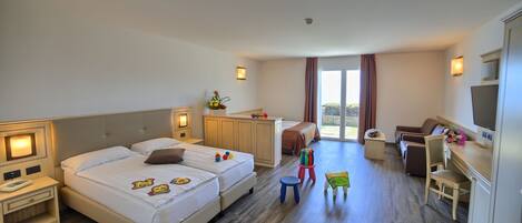 Habitación de hotel con dos camas, un escritorio, una silla, un televisor y una mesita con un florero.