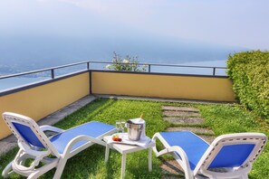 Een terras met twee witte lounge fauteuils en een klein tafeltje, een emmer ijs en twee champagneglazen.