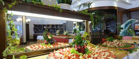 A buffet with various food items and decorative plants.