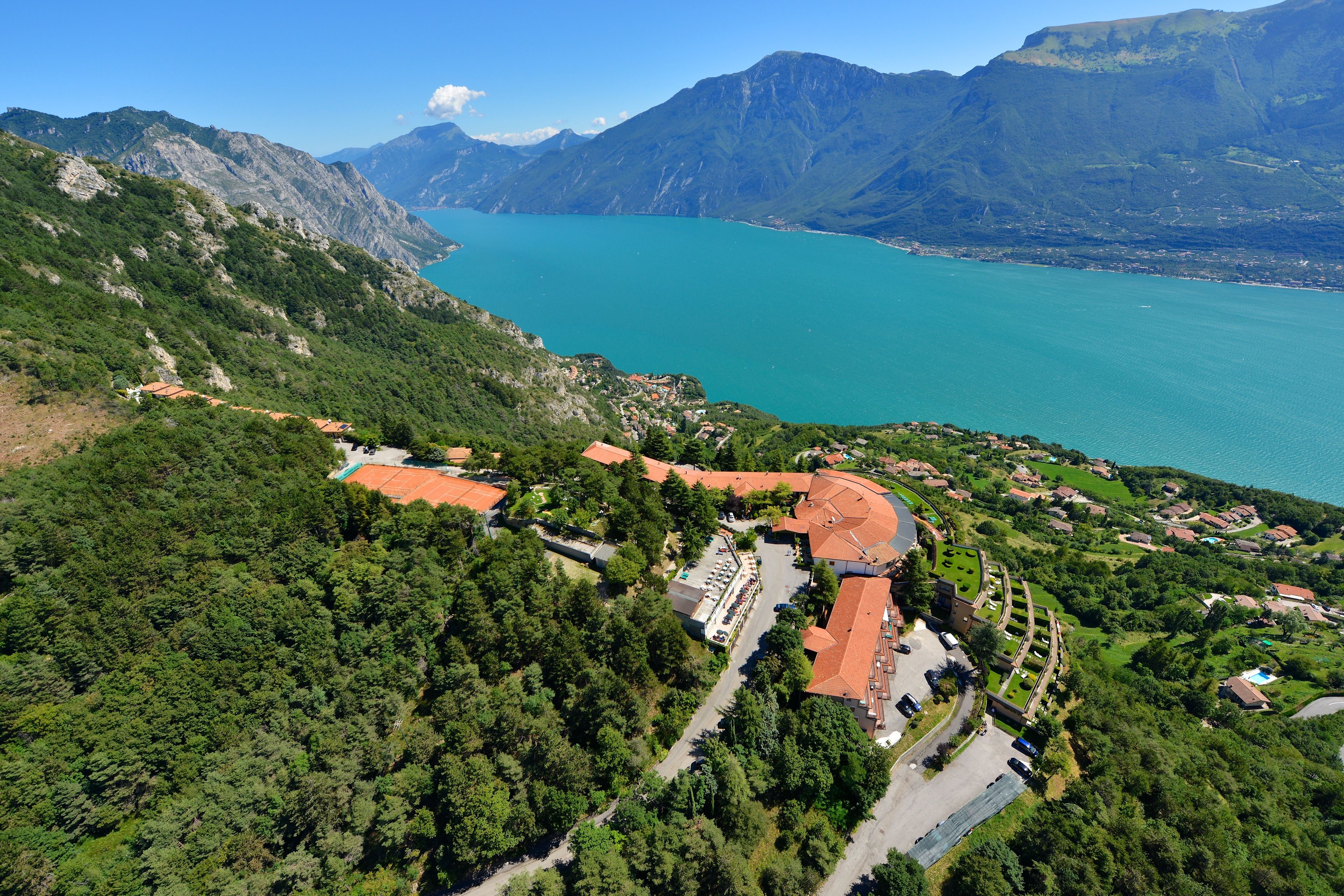 An aerial view of a coastal town with a large body of water, surrounded by mountains and greenery.