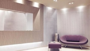 Un intérieur moderne avec un mur texturé, un fauteuil violet et une petite table.
