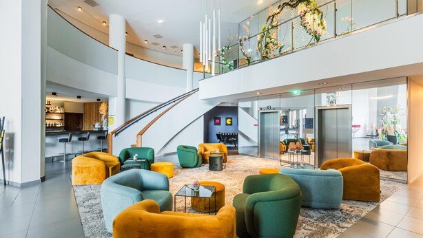 A spacious lobby with a high ceiling, a staircase, and a bar area.