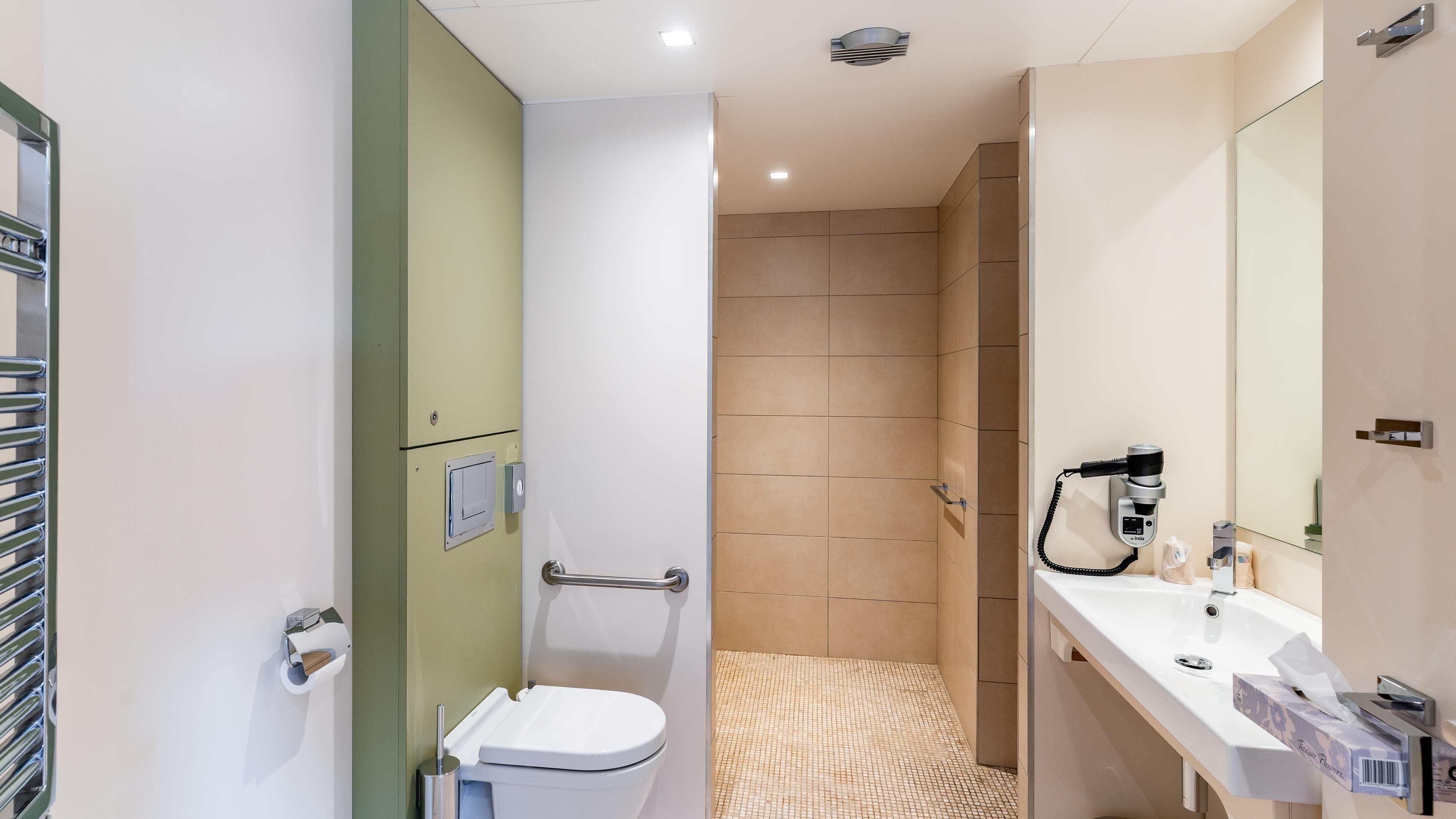 Un baño moderno con inodoro, bidé y secador de pelo en la encimera.