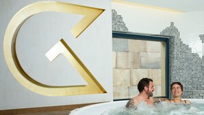 A couple in a hot tub with a large wall decoration.