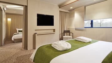 A hotel room with a bed, a TV, a chair, and a window.