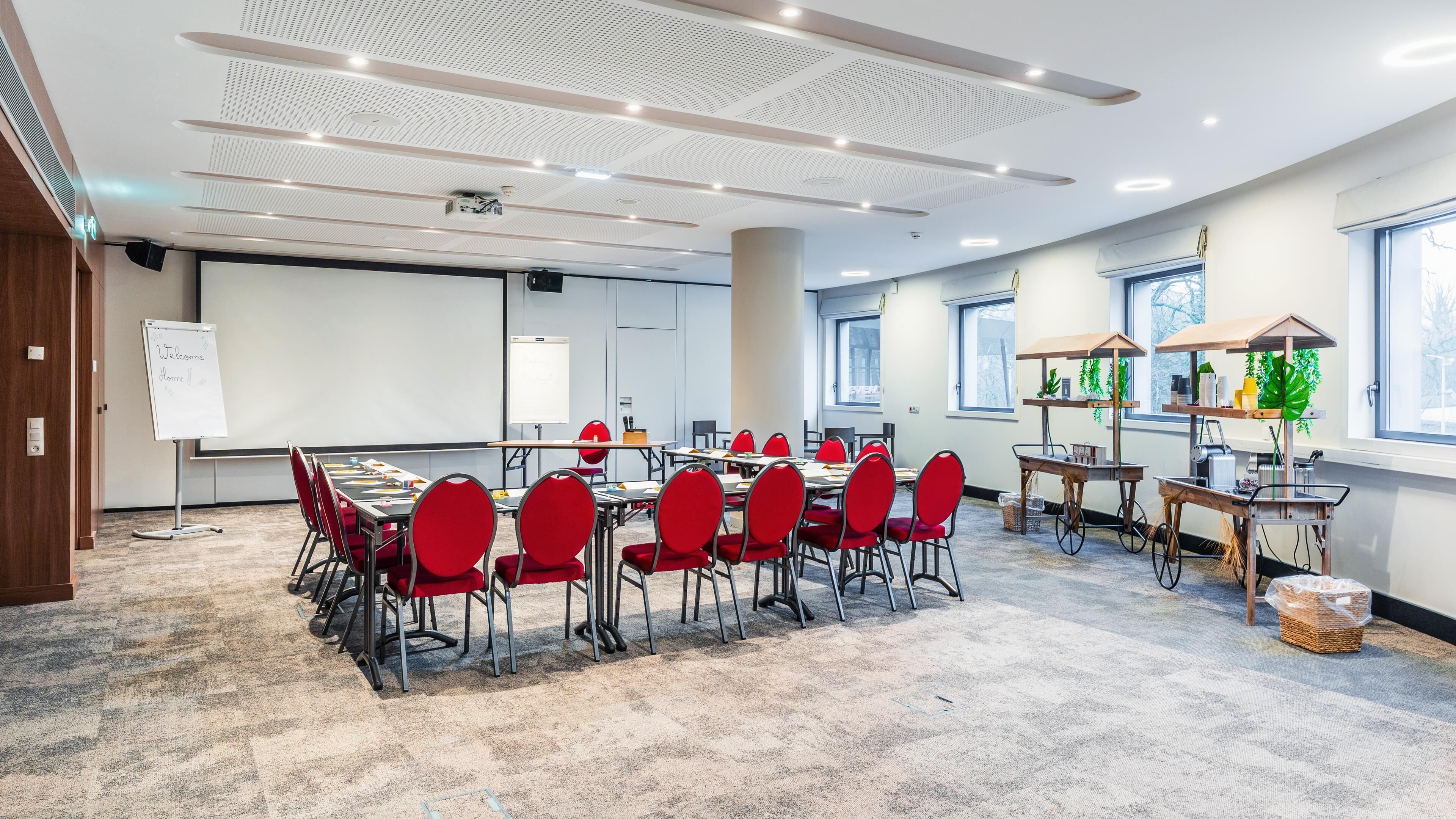 A conference room with a whiteboard, red chairs, a projector, and a large window.