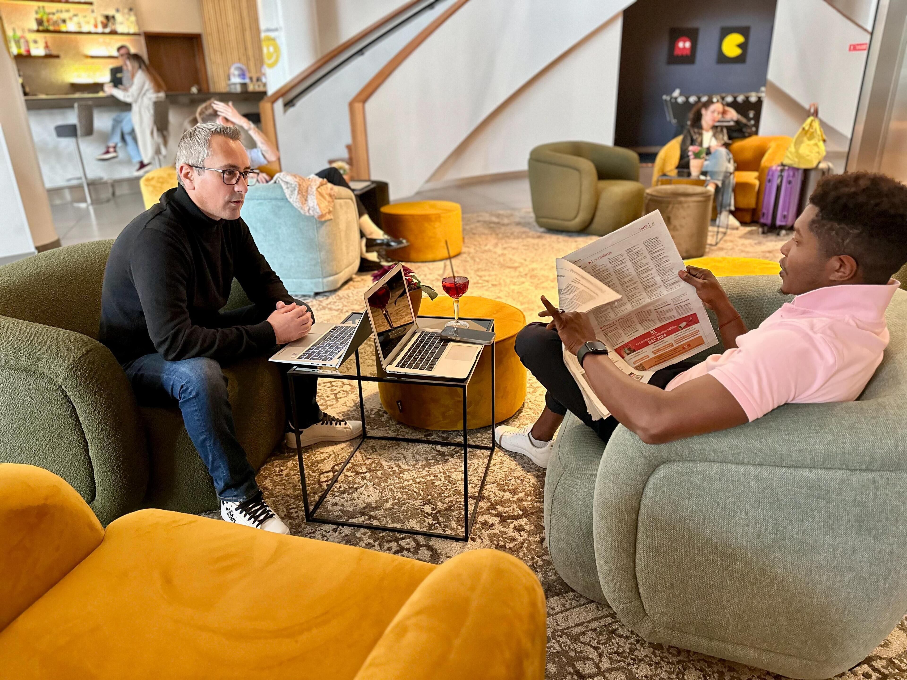 Ett modernt loungeområde med bekväma sittplatser, ett soffbord och en bärbar dator på ett litet bord.