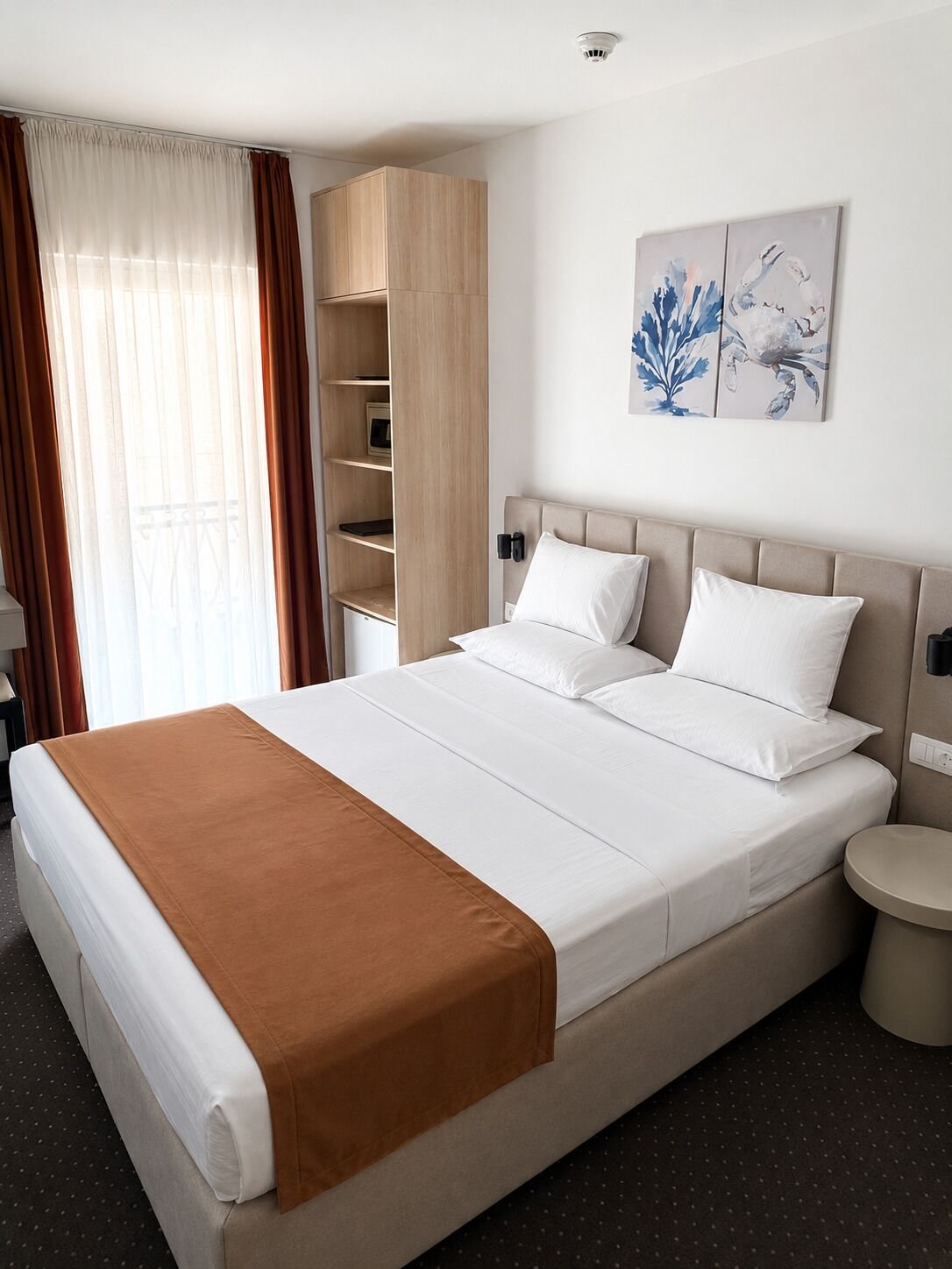 Habitación de hotel con cama, mesita de noche, armario y un cuadro en la pared.