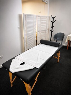 A medical examination table with a white sheet, a black mattress, and wooden legs. - Garni Hotel Fineso (Budva)
