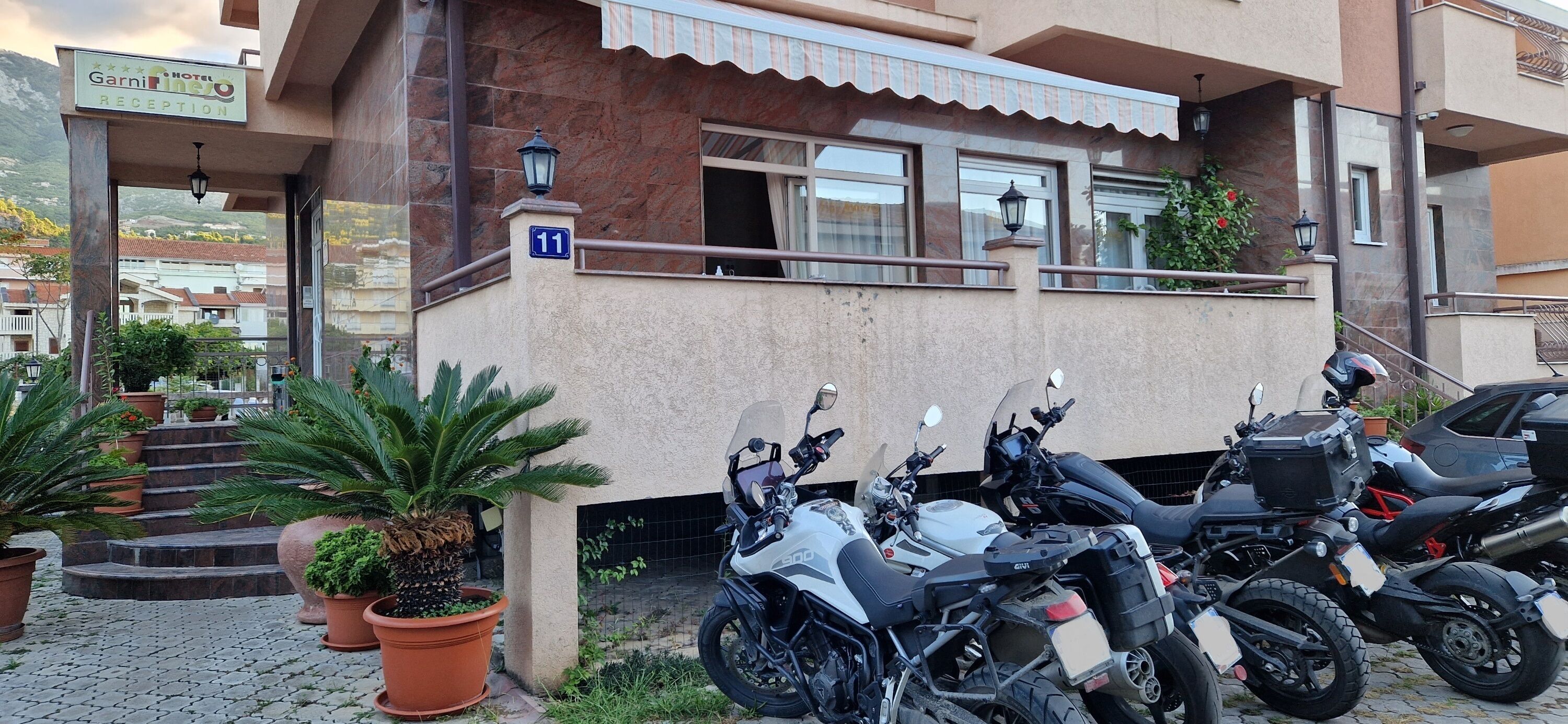 Una recepción de hotel con un letrero, el número 11, y dos motocicletas estacionadas frente a ella.