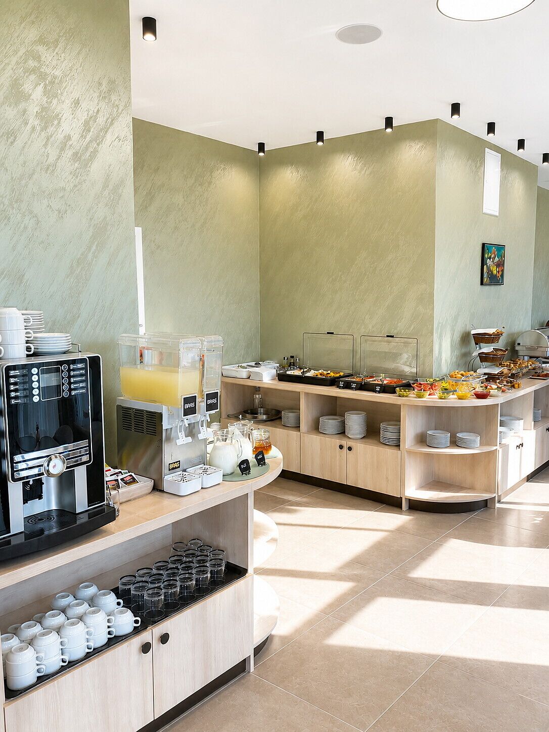 Una mesa de buffet con una máquina de café, dispensadores de bebidas y diversas opciones de comida.