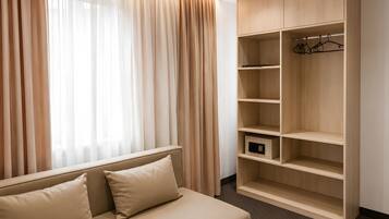 Una habitación con cama, armario y ventana con cortinas.