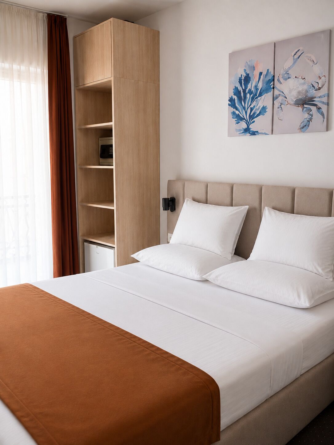 Una habitación de hotel con una cama, un armario, una mesita de noche y una obra de arte en la pared.