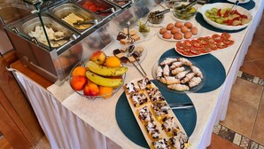 Un bufé con diversos alimentos, entre ellos frutas, pasteles y postres.