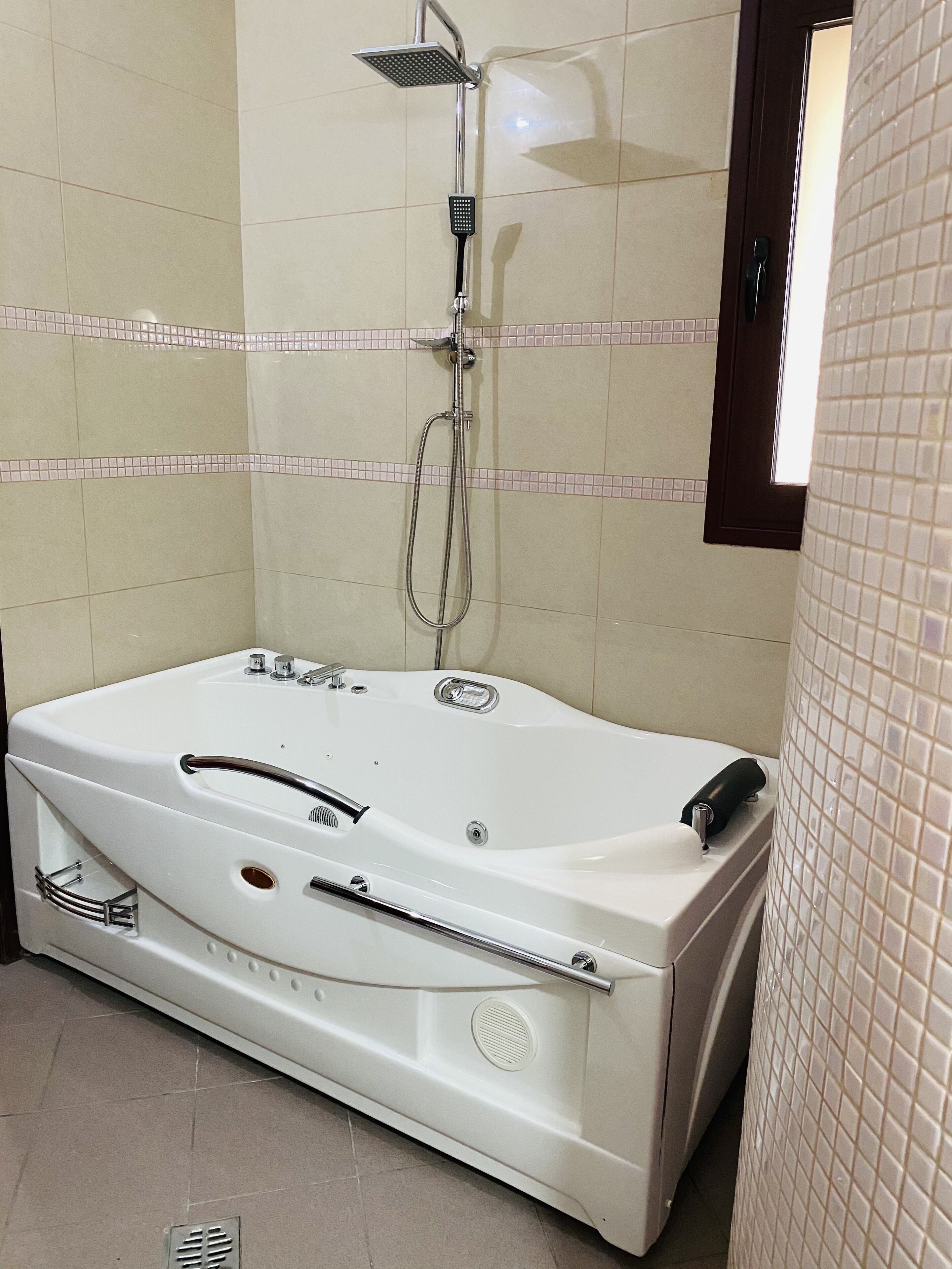 Ein modernes Badezimmer mit einer großen Badewanne, einer Handbrause und einem wandmontierten Wasserhahn.
