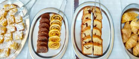 Una mesa de buffet con diversas opciones de panadería, incluyendo pasteles y pan.