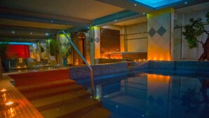 A hotel lobby with a swimming pool, a staircase, and a reception area.