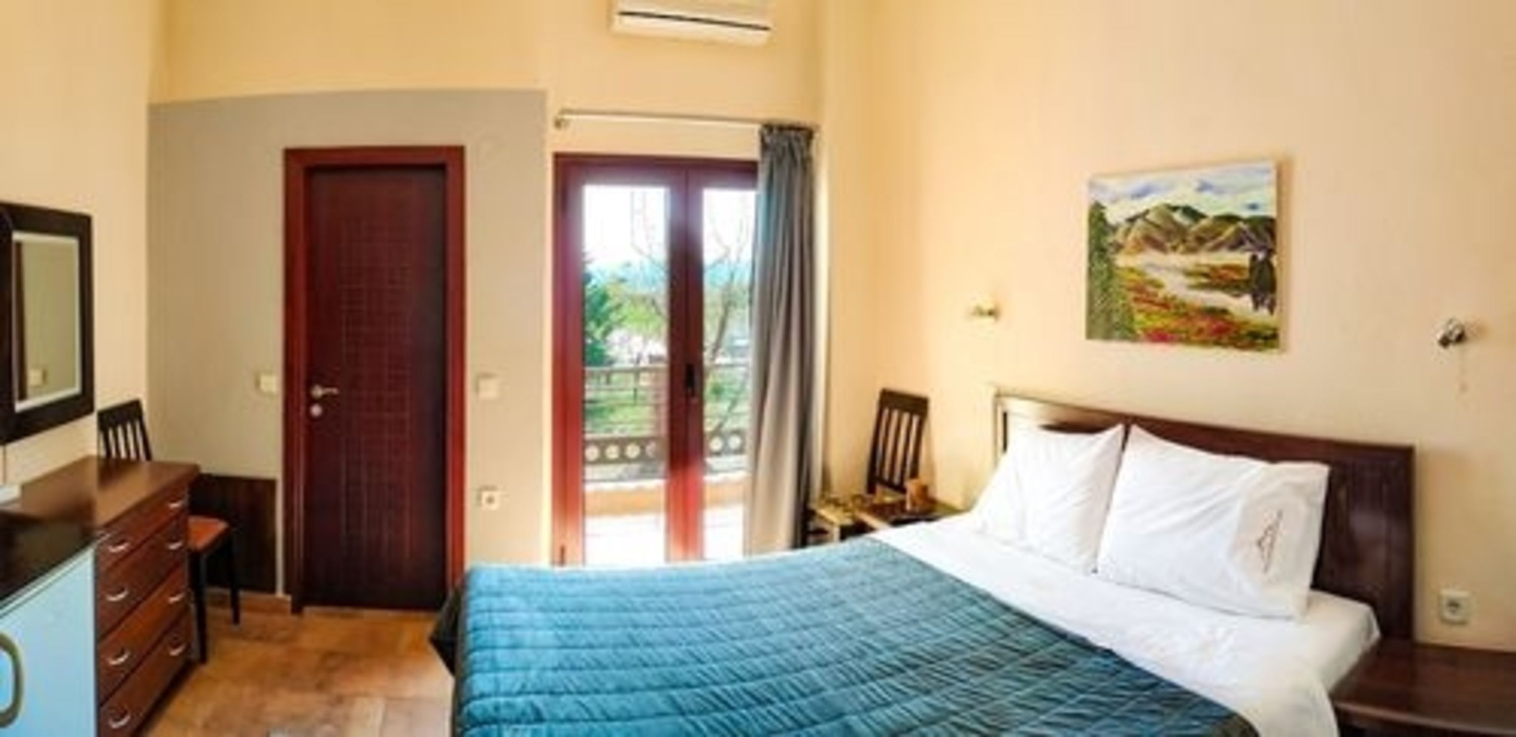 Ein Schlafzimmer mit einem Bett, einem Schminktisch, einer Tür und einem Bild an der Wand.