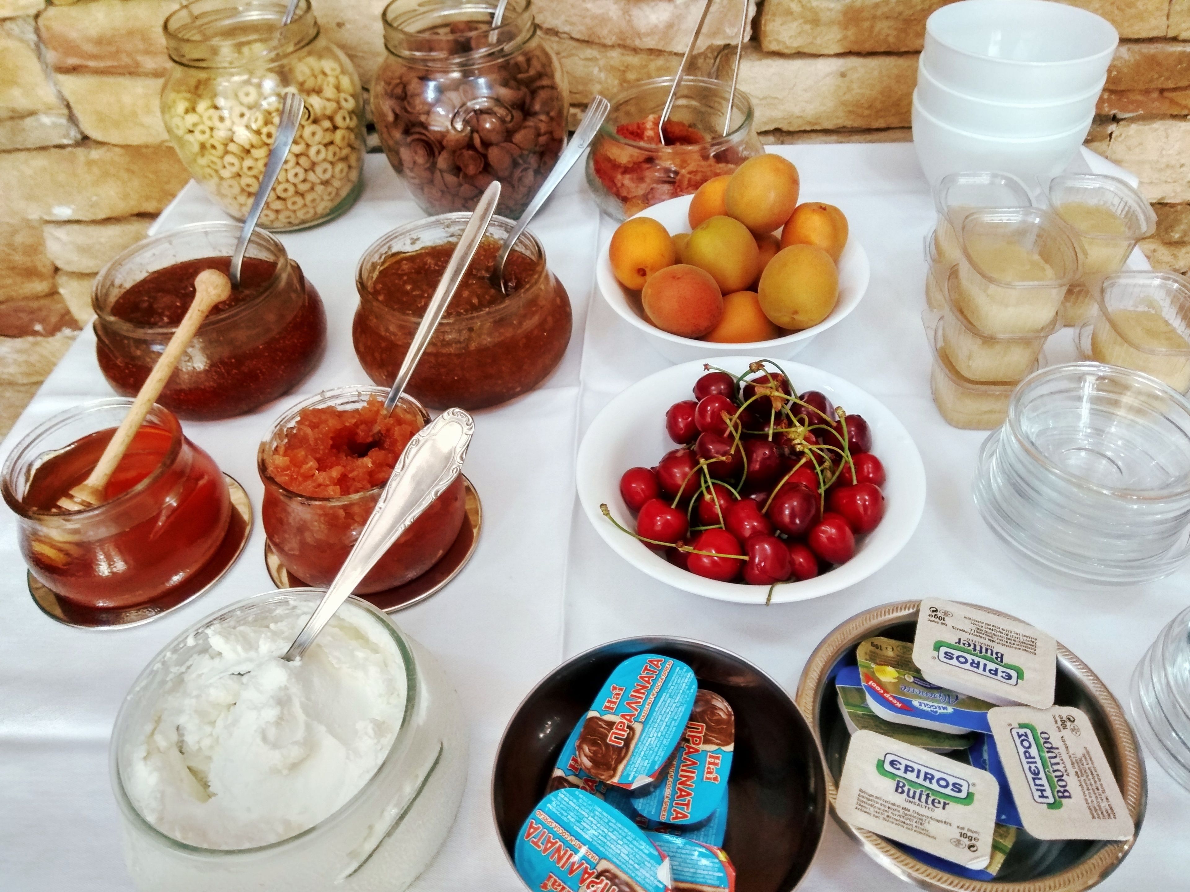 Una mesa con diversos alimentos, incluyendo frascos de conservas, un tazón de cerezas y productos alimenticios envasados.