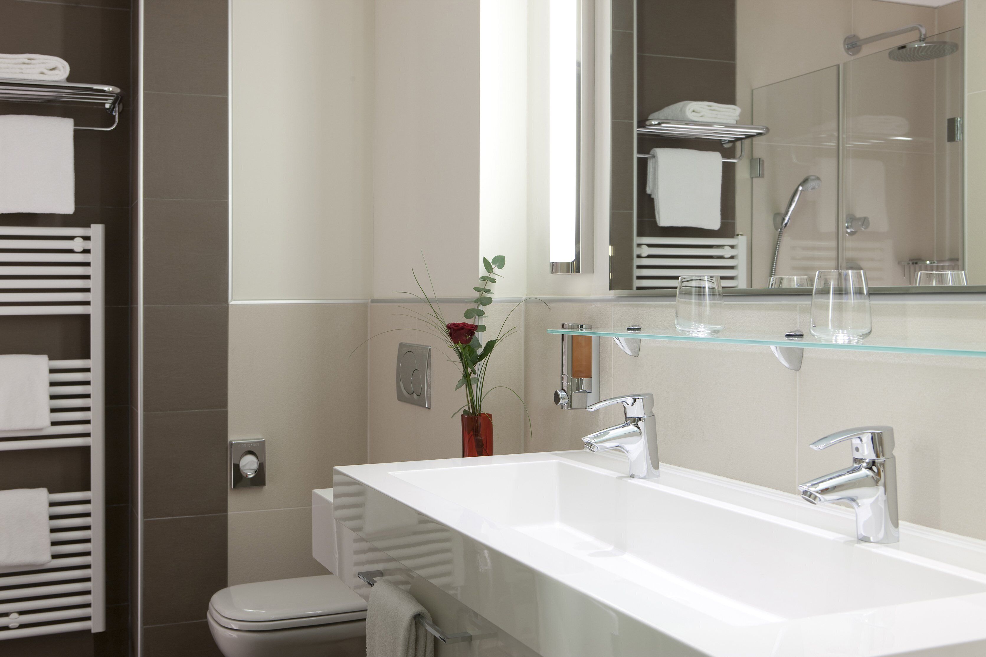 Un baño moderno con un espejo grande, dos lavamanos y una ducha.
