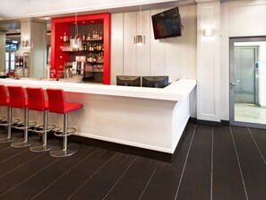 Enjoy a drink at the sleek bar, featuring a long counter and comfortable seating.